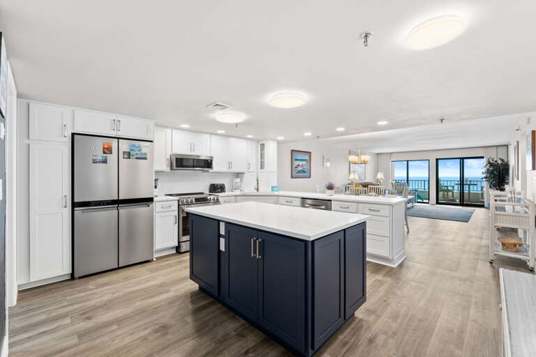 Open kitchen with elegant marble countertops, island seating, and stainless steel appliances.