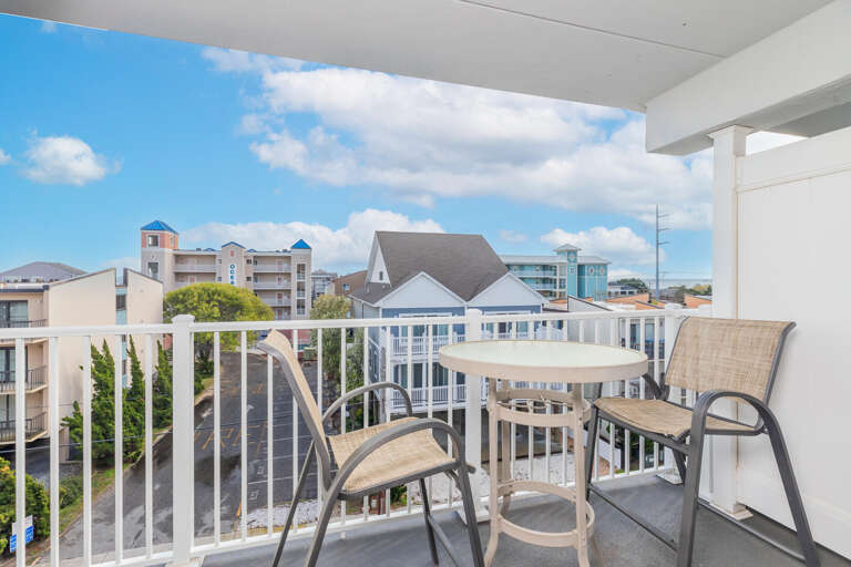 Balcony View Of Bustling Street With Buildings, Blue Sky Backdrop