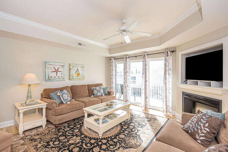 Living Space With Sofa, Table, Fireplace, Television, And Balcony Access