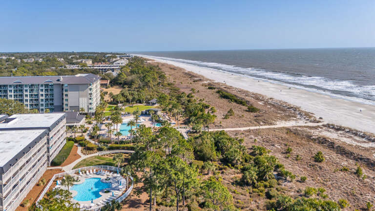 Aerial View Of Beachfront Buildings With Swimming Pools And Coastline