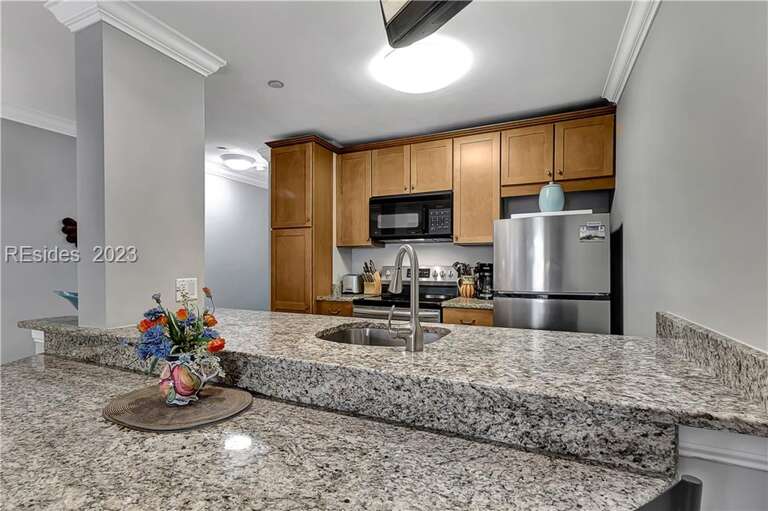 Beautiful granite countertops and attached dining table looks into a fully equipped kitchen.