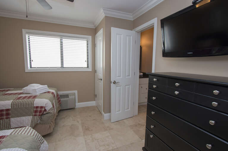 The nicely furnished second bedroom has a pair of twin beds and a wall mounted flat screen television
.A hallway bath is provided for this bedroom.