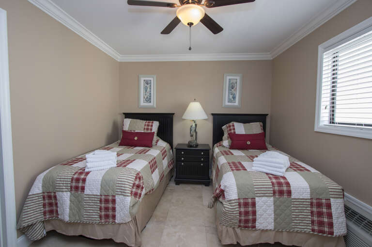 The nicely furnished second bedroom has a pair of twin beds and a wall mounted flat screen television.
A hallway bath is provided for this bedroom.