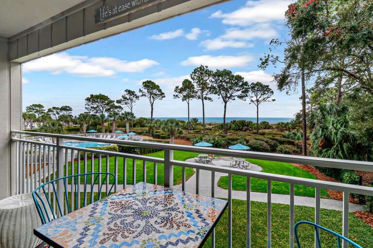 Balcony View With Table Overlooking Trees And Sea
