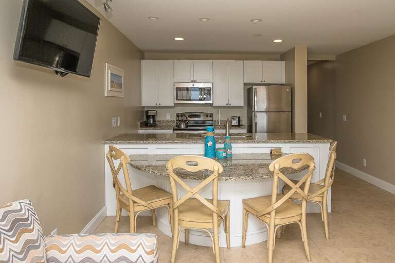 Completely furnished kitchen that looks to dining area and ocean view