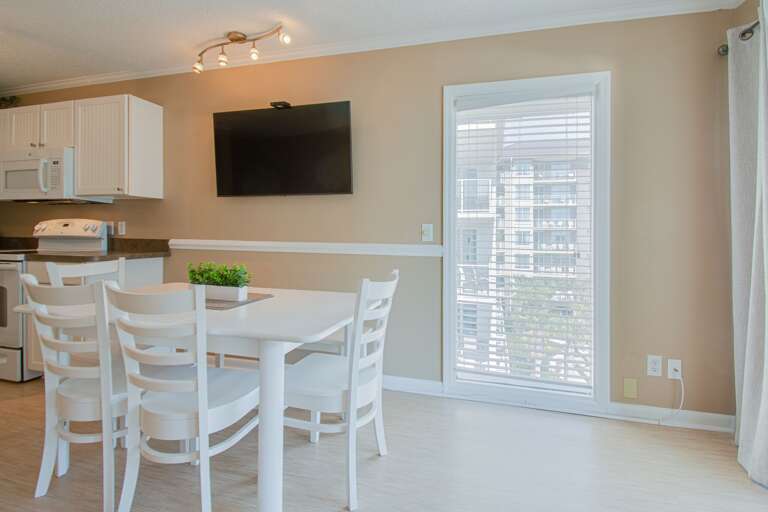 Interior Dining Space With White Furniture And Mounted TV