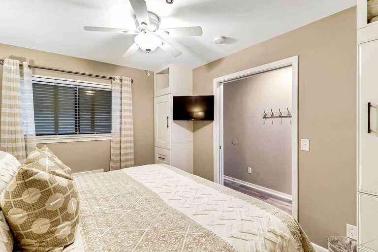 Relaxing, renovated bedroom with ceiling fan, wall mounted TV and plenty of storage.  