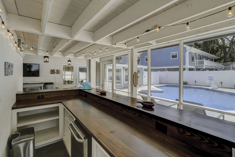 Screen in porch with flat screen TV and poolside bar. 