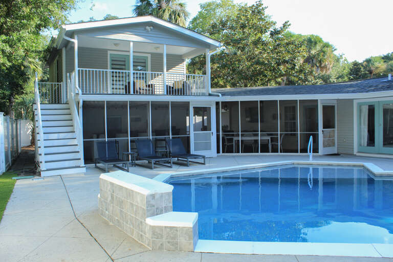 Blue Pool Beside A Two-story Vacation Rental With Balcony
