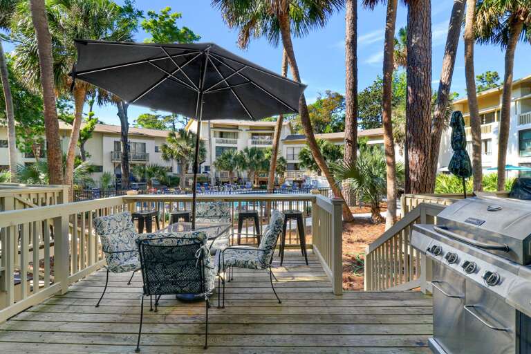 Deck offers grill nice view overlooking the pool. Table with umbrella seats four  .