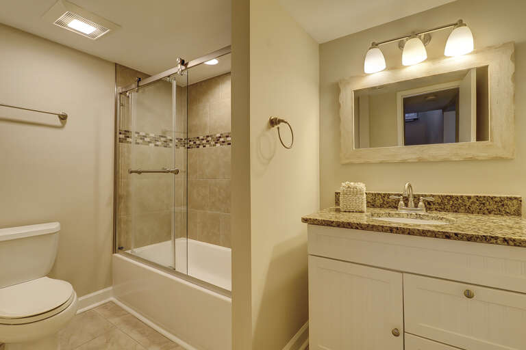 Beautiful updated bathroom with granite countertops and tiled shower surround. 
