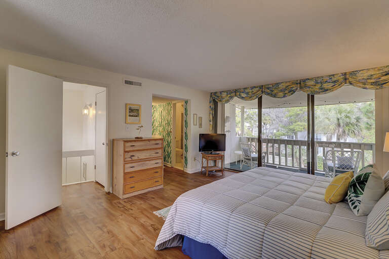 Spacious master bedroom with king sized bed,  ensuite bathroom and private balcony overlooking a lagoon.   