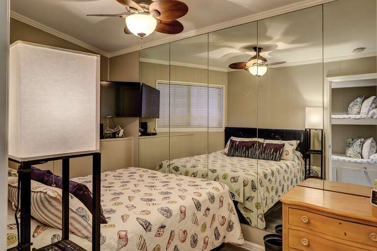 Interior Of A Room With Two Beds, Ceiling Fans, And A Television