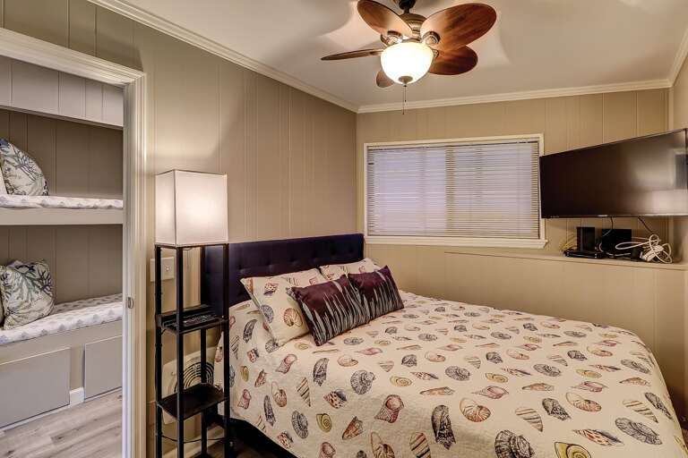 Interior Of A Bedroom With Patterned Bedding And Ceiling Fan