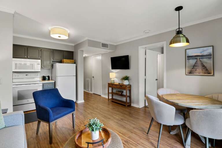 Interior Of A Residential Living Space With Kitchen, Dining Table, And Chairs
