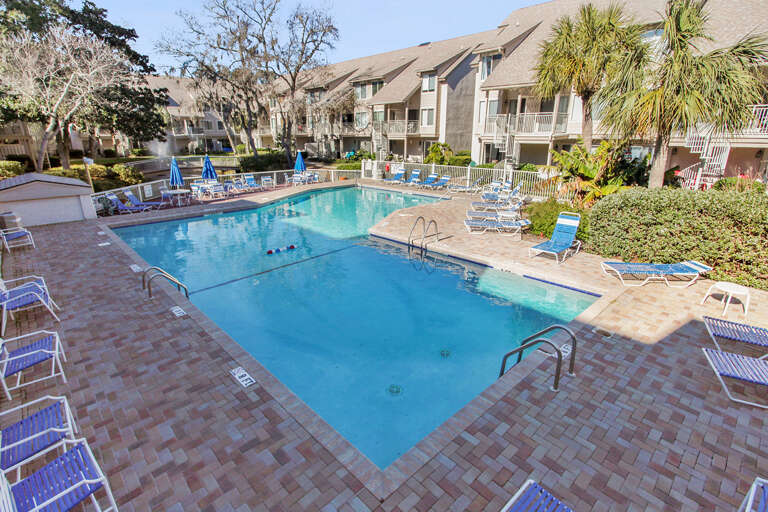 Swimming Pool With Sun Loungers And Surrounding Buildings