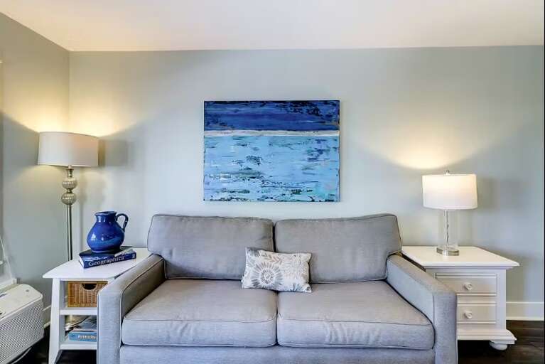 Living Room With Sofa, Table Lamps, And Wall Art