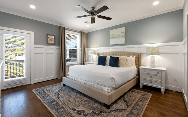 Drift into comfort in this serene bedroom with a plush king bed, gentle ceiling fan, and elegant wainscoting that creates your perfect retreat.