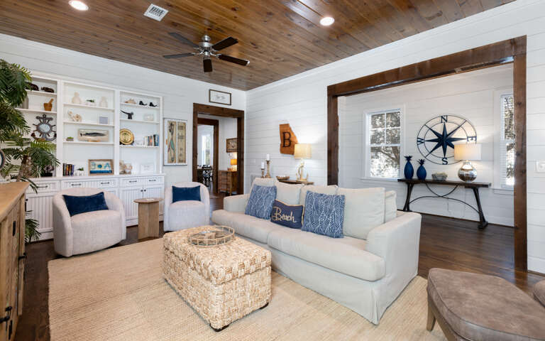 Sink into plush coastal comfort where rustic wood ceilings meet crisp white walls, creating your perfect beach retreat sanctuary.