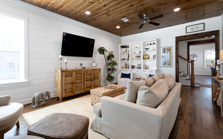 Sink into the plush sectional sofa and enjoy movie nights on the large TV in this stylish living room with rustic wood ceiling.