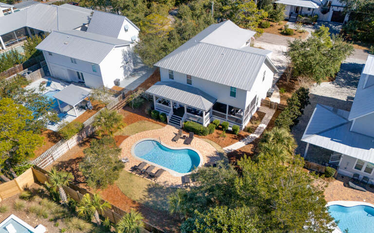 This spacious beach house features a stunning kidney-shaped pool surrounded by tropical landscaping in a peaceful residential neighborhood.