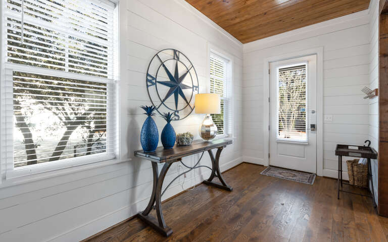 Step into your charming coastal-inspired entryway, where natural light streams through custom blinds and warm wood floors welcome you home.