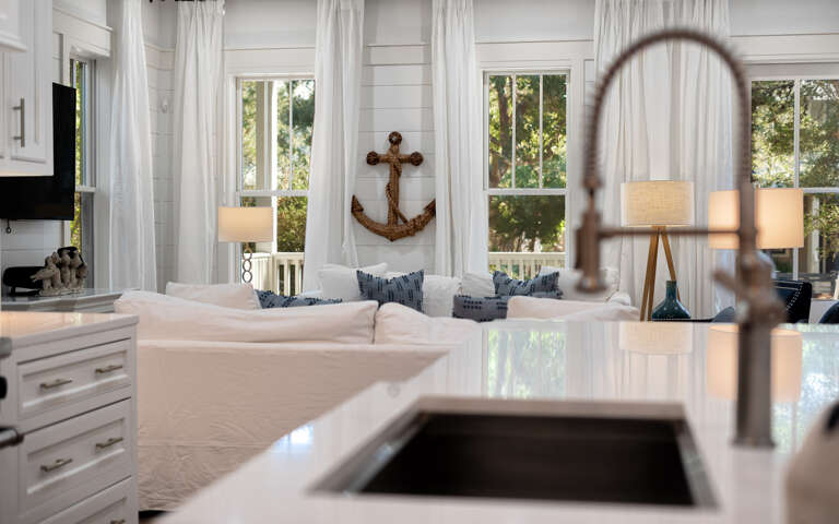 Your bright kitchen flows seamlessly into the cozy living space, where nautical charm meets modern comfort beneath soft natural light.