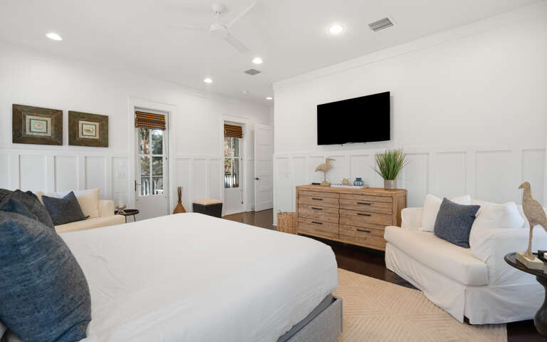Relax in your elegant master suite with coastal charm, complete with seating area and mounted TV for cozy nights in.