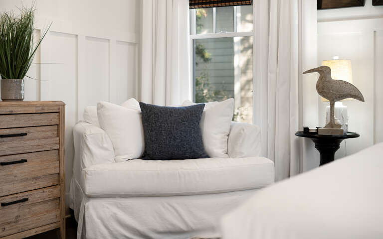 Relax in your serene reading nook with crisp white linens and coastal charm, where soft light filters through for peaceful moments.