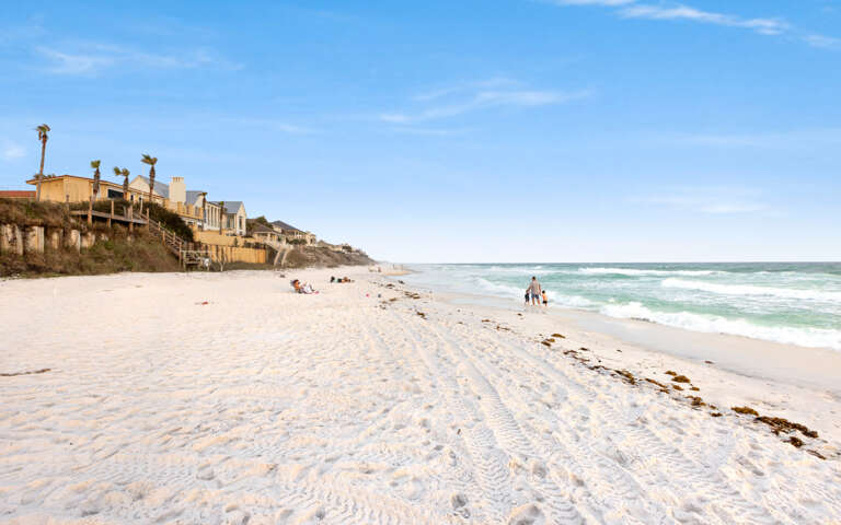 Beach Scene With Buildings In The Background And People On Sand