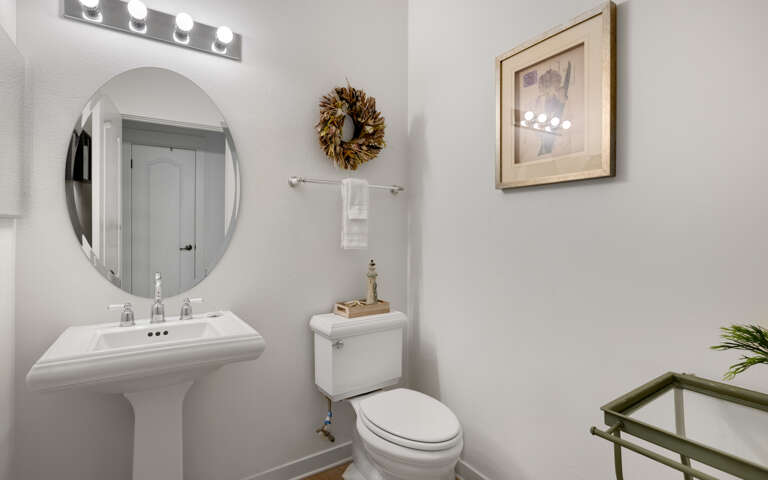 Fresh your morning routine in this thoughtfully appointed powder room, featuring elegant vanity lighting and welcoming touches.