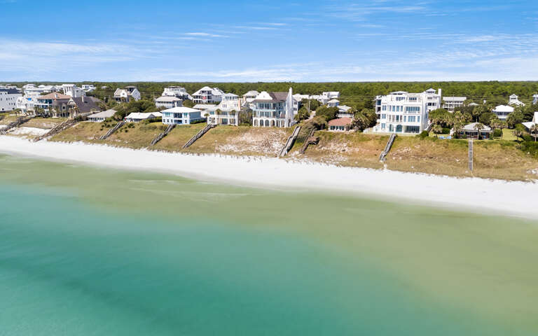 Stunning gulf front properties line pristine white sand shores with crystal-clear turquoise waters stretching to the horizon.