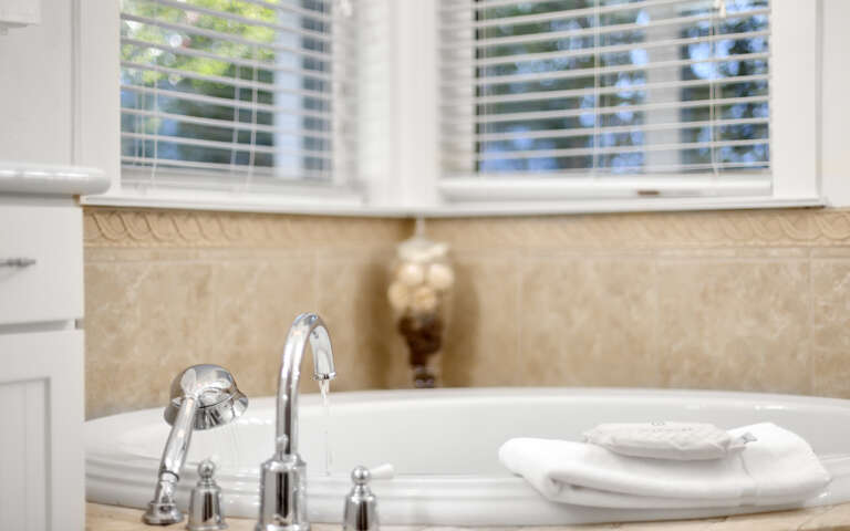 Slip into your private spa-like bathtub where warm natural light filters through blinds, creating the perfect sanctuary for relaxation.