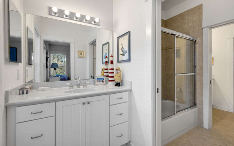 Your spacious bathroom features coastal charm with nautical décor, vanity lighting, and a relaxing shower-tub combo for unwinding after beach days.