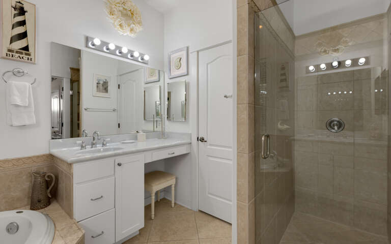 Refresh in your elegant bathroom featuring dual vanities, sparkling mirrors, and a luxurious walk-in shower with beautiful tiling.