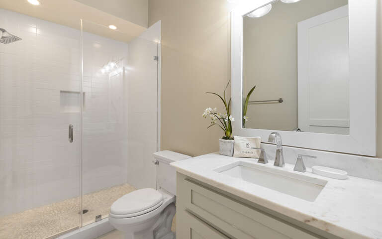 Step into your pristine bathroom where marble countertops and a spacious glass shower create a spa-like retreat for your daily rituals.