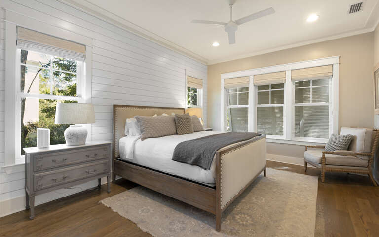 Unwind in this elegant bedroom with crisp white linens and natural light streaming through large windows.