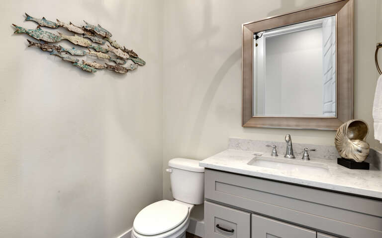 Your elegant powder room features coastal charm with artistic fish decor, marble countertops, and quality fixtures for your comfort.