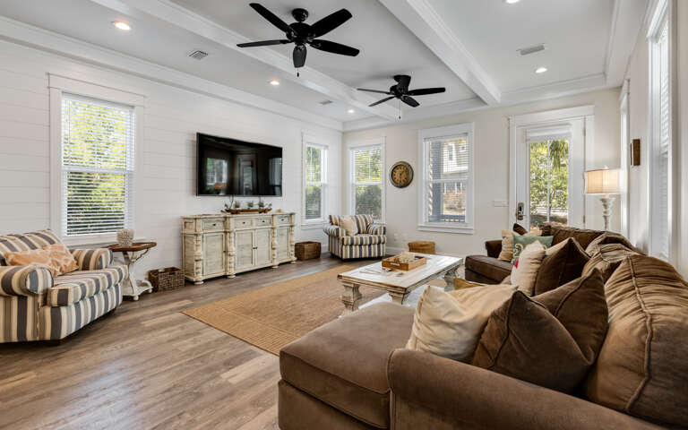 Sink into plush seating while ceiling fans keep you cool in this elegant living space with warm wood floors and abundant natural light.