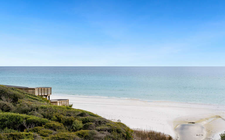Pristine beach with crystal-clear turquoise waters stretching to the horizon under endless blue skies.