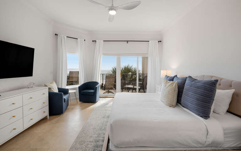 Wake to coastal views from your bright bedroom, complete with balcony access and thoughtful touches like cozy seating.