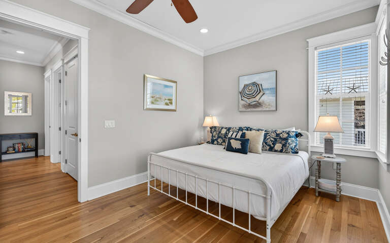 Relax in your peaceful bedroom with coastal charm, where warm wood floors and beach-inspired art create the perfect retreat.