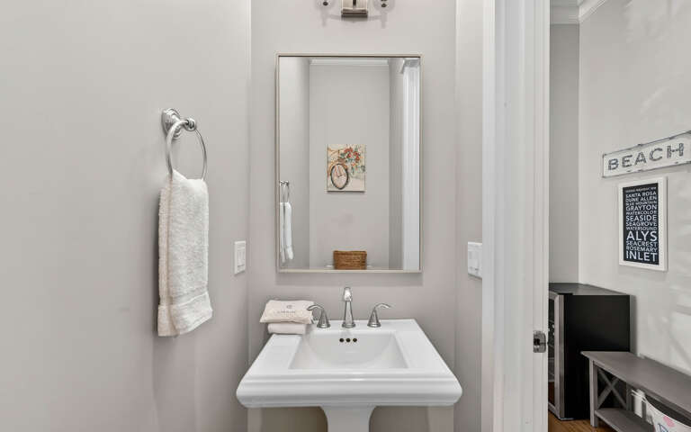 Refresh in your stylish powder room with coastal charm, featuring crisp white fixtures and thoughtful beach-themed touches.