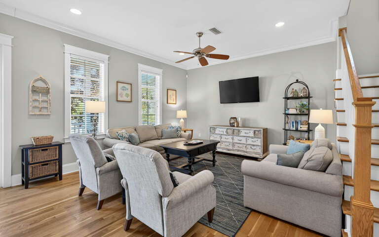 Relax in your spacious living room with comfortable seating, modern entertainment, and abundant natural light streaming through tall windows.