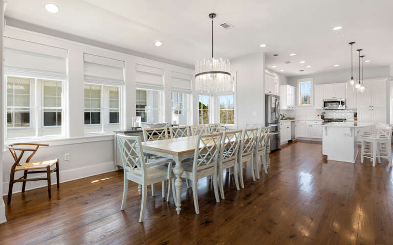 Gather around your elegant dining table with crystal chandelier overhead, then step into your fully-equipped white kitchen with modern appliances and island seating.