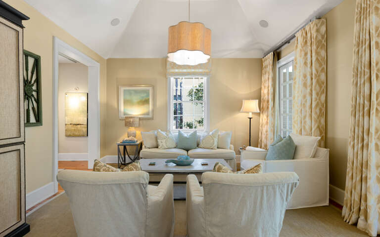 Your elegant living room awaits with plush seating, warm lighting, and peaceful views through tall windows.