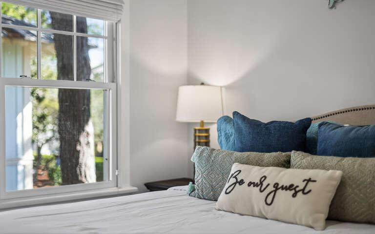 Sink into plush pillows and cozy textures in your beautifully appointed bedroom, where morning light streams through charming windows.