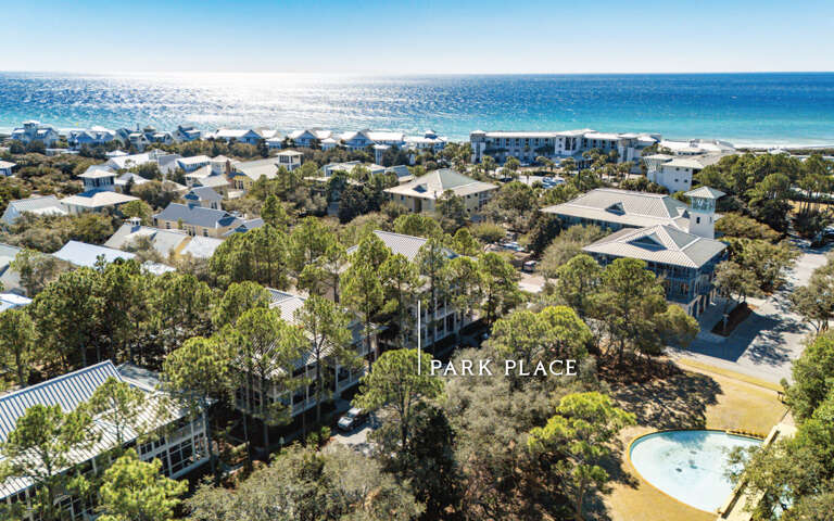 Aerial view of coastal vacation homes nestled among lush trees with crystal blue waters and pristine beach nearby.