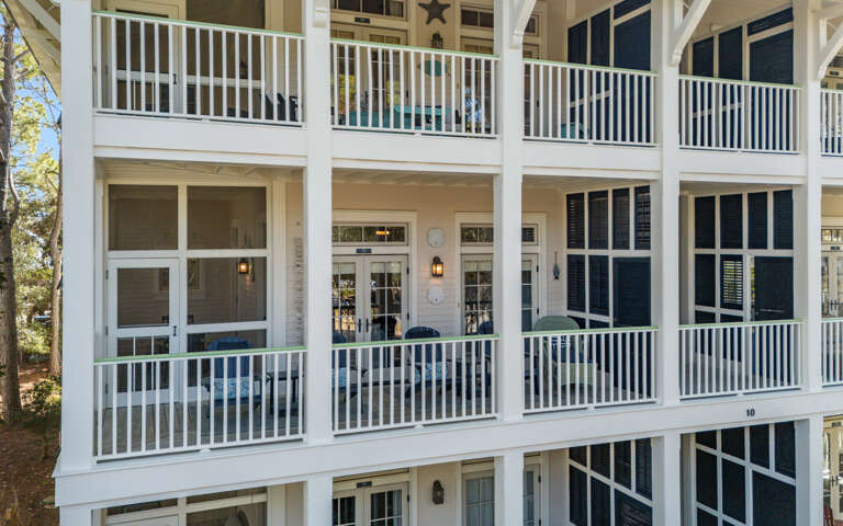 Bright two-story building featuring classic white railings and large windows in a peaceful setting.