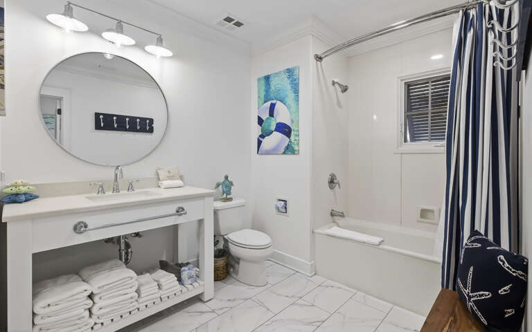 Unwind in this bright, modern bathroom featuring a soaking tub and coastal-themed touches that make your stay feel serene.